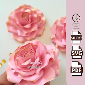 Puede incluir: Tres rosas de papel rosa con bordes dorados. Las rosas están superpuestas y tienen un aspecto delicado y plisado. El texto "Angelic's Workshop" es visible en la rosa de abajo. La imagen también incluye iconos para descarga instantánea en los formatos Studio, SVG y PDF.