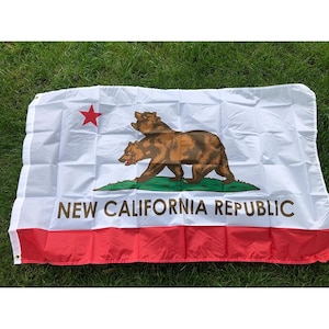 Op de afbeelding: Een witte vlag met een bruine beer die op een groen stuk gras loopt, een rode ster in de linkerbovenhoek en de tekst NEW CALIFORNIA REPUBLIC in bruine hoofdletters boven een horizontale rode streep langs de onderkant.