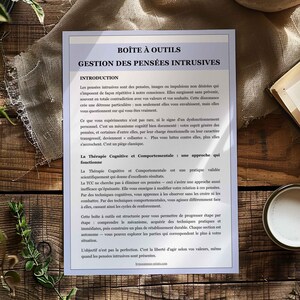 May include: A printed document titled "BO&Icirc;TE &Agrave; OUTILS GESTION DES PENS&Eacute;ES INTRUSIVES" on a wooden surface. The document has text in French, with sections like "INTRODUCTION" and "La Th&eacute;rapie Cognitive et Comportementale".