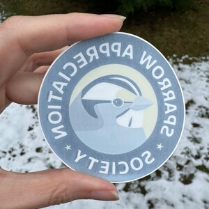 May include: A round sticker with a blue jay illustration and the text "Society for Appreciation" in a circle around the bird.