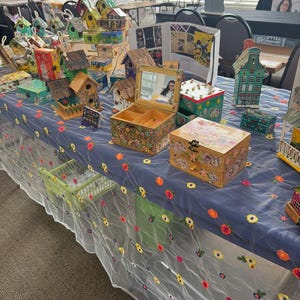 K&ouml;nnte beinhalten: Ausstellung handgefertigter dekorativer Schachteln und Vogelh&auml;user. Die Schachteln weisen florale und architektonische Designs auf, mit einer Vielzahl von Farben und Gr&ouml;&szlig;en. Einige haben Spiegel oder Schubladen. Die Vogelh&auml;user sind Miniatur- und farbenfroh.