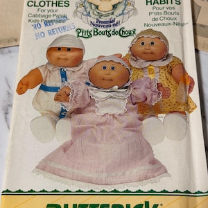 Peut inclure: Un patron de couture Butterick vintage pour les vêtements des Cabbage Patch Kids. Le patron présente des illustrations de trois poupées Cabbage Patch Kids portant différentes tenues. Le patron comprend les textes "Clothes" et "Habits".