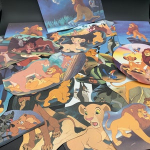 May include: A collection of colorful cartoon lion character cutouts, featuring various poses and expressions. The cutouts are arranged in a pile, with some overlapping. The characters are all from the Disney movie The Lion King.