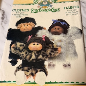 May include: A vintage Butterick pattern envelope featuring three Cabbage Patch Kids dolls in furry outfits. The envelope has text that reads "CLOTHES" and "HABITS" with the Cabbage Patch Kids logo. The pattern number is 6984.