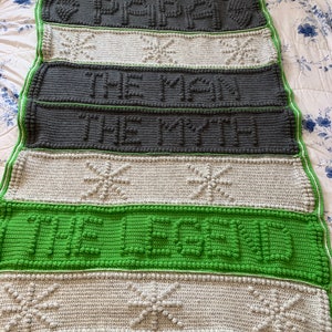 May include: A green, white, and gray crocheted blanket with the words "Papa, The Man, The Myth, The Legend" written in raised letters.