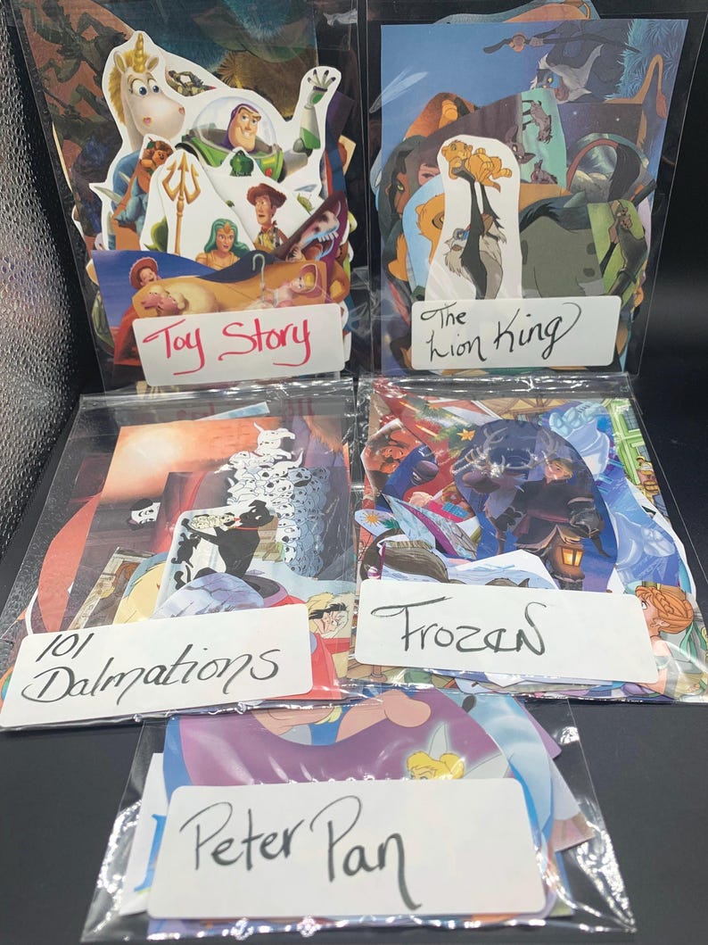 May include: Five clear plastic bags each containing a stack of colorful cartoon character stickers. The bags are labeled with the names of the movies the stickers are from: Toy Story, The Lion King, 101 Dalmatians, Frozen, and Peter Pan.