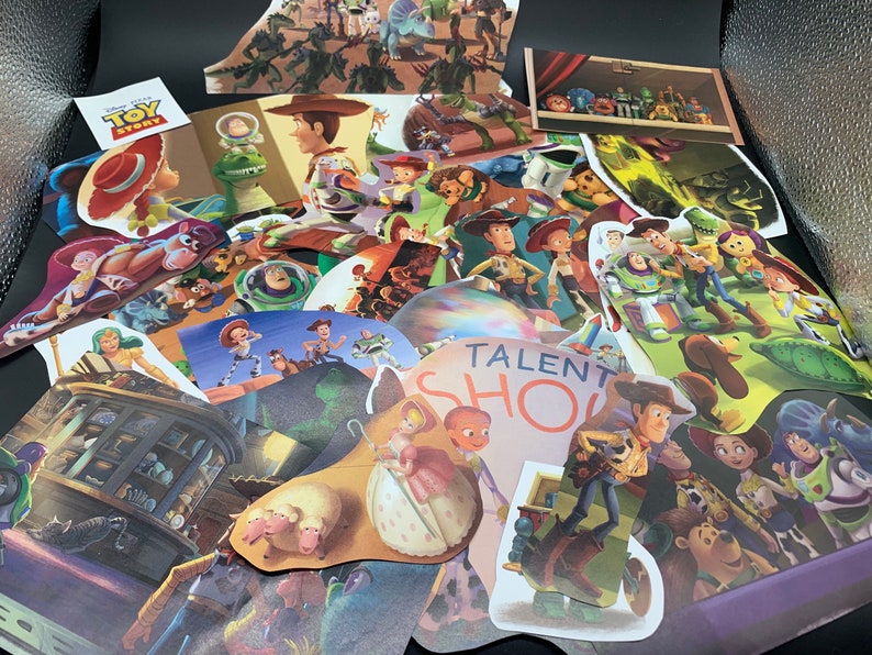 May include: A collection of colorful paper cutouts featuring characters from the Toy Story franchise. The cutouts include Woody, Buzz Lightyear, Jessie, and other characters from the movie. The cutouts are arranged in a random order and are all different sizes. The cutouts are on a black background.