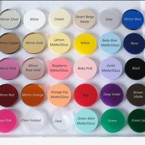 May include: A display of various colored acrylic circles, each labeled with a color name. Colors include mirror silver, white, cream, desert beige, grey, mirror blue, mirror copper, mirror gold, lemon, yellow, baby blue, navy, mirror pink, mirror rose gold, raspberry, baby pink, violet, black, mirror red, mirror orange, orange fizz, red, deep violet, brown, deep pink, clear frosted, clear, green mint, green, and green sage.