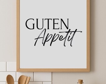 May include: A framed print with the words "Guten Appetit" in black script. The wooden frame surrounds a white background. A ceramic utensil holder with wooden spoons and a bottle of olive oil are in the foreground.