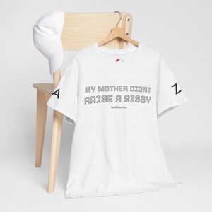 Pode incluir: Uma t-shirt branca de manga curta com o texto preto MY MOTHER DIDNT RAISE A SISSY e SpazApulse na frente, a letra A na manga direita e Z na manga esquerda, acompanhada por um boné de basebol branco a combinar.