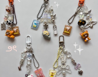 Può includere: Cinque portachiavi colorati con ciondoli, perline e piccole figurine. Ogni portachiavi presenta un piccolo animale dei cartoni animati, una piccola busta di patatine e altri ciondoli decorativi. I portachiavi sono attaccati a anelli portachiavi argentati.