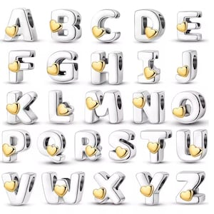 Peut inclure: Collection de breloques alphabet argentées, chacune ornée d'un cœur doré. Les breloques sont conçues pour être enfilées sur un bracelet ou un collier. Les lettres de A à Z sont affichées.