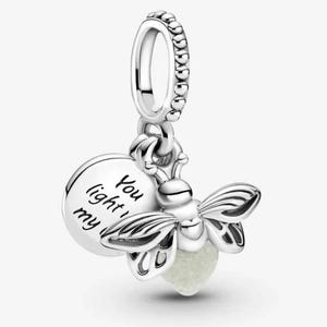 Può includere: Un charm d'argento con un design a lucciola. Il charm presenta un disco rotondo con le parole "You light my" e una lucciola con accenti verdi luminosi. Il charm è sospeso da un anello di perline.