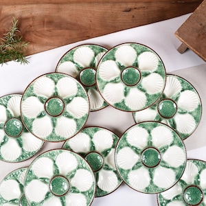 Può includere: Set di sei piatti per ostriche in ceramica bianca con bordi verdi a forma di conchiglia e un cerchio centrale verde. Ogni piatto ha sei incavi individuali a forma di conchiglia.
