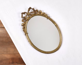 Miroir ovale en métal, doré. Noeud style Louis XVI. Authentique miroir ancien, style classique pour décoration murale.