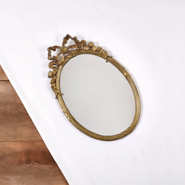 Miroir ovale en métal, doré. Noeud style Louis XVI. Authentique miroir ancien, style classique pour décoration murale.