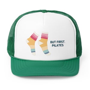 May include: A white and green trucker hat with a colourful sock design and the text "BUT FIRST, PILATES".