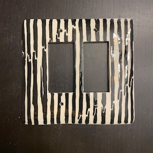 May include: A white and black striped double light switch cover with a glossy finish.