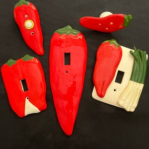 May include: Set of six red and green ceramic light switch covers shaped like chili peppers and a green onion.