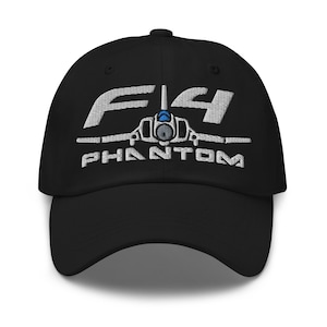 Może przedstawiać: Czarna czapka bejsbolówka z haftowanym na biało logo F-14 Phantom. Logo przedstawia stylizowaną sylwetkę samolotu z napisem "F-14 PHANTOM" poniżej.