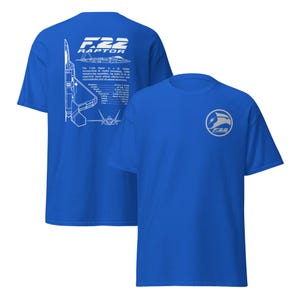 May include: Two blue t-shirts with a white design of an F-22 Raptor fighter jet. The back of the shirt has a diagram of the jet with specifications. The front of the shirt has a logo with the text "F-22 Raptor".
