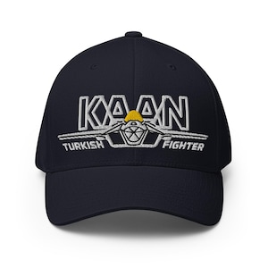 Peut inclure: Casquette de baseball bleu marine avec texte brodé blanc et un motif. Le texte indique "KAAN TURKISH FIGHTER". Le motif est un avion stylisé avec un accent jaune.