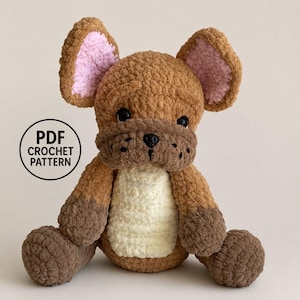 May include: A brown and cream crochet plush toy shaped like a dog with large upright ears featuring pink inner accents, black plastic eyes, and a dark brown muzzle. A circular black icon on the left displays the text PDF CROCHET PATTERN.