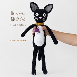 May include: A black and white crochet cat toy with a yellow collar and a small purple spider attached. The text on the image reads: Halloween Black Cat, Crochet pattern, EASY AMIGURUMI. The cat has white eyes, a pink nose, and white whiskers.