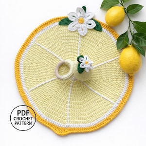 Può includere: Un giocattolo per bambini a forma di fetta di limone all'uncinetto, con un anello di legno e un piccolo fiore. Il giocattolo è giallo, bianco e verde, con un fiore a forma di margherita in cima. È presente anche il testo "PDF CROCHET PATTERN".