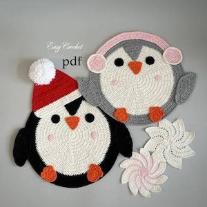 May include: Handmade crochet penguin coasters and snowflake decorations. One penguin has a red and white hat, the other has pink earmuffs. The coasters are white, black, grey, and orange. The text "Easy Crochet pdf" is visible.