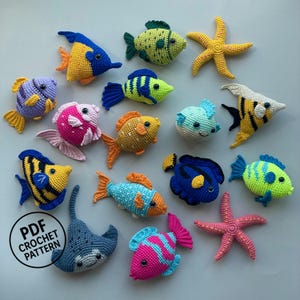 May include: A collection of colorful crocheted sea creatures including various fish, two starfish, and a stingray. The set features vibrant yarn colors like blue, yellow, pink, and green. A circular black logo with the text PDF CROCHET PATTERN is visible.