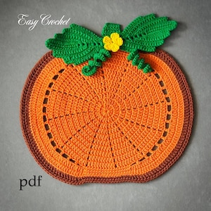 Op de afbeelding: Een gehaakte pompoenvormige placemat in oranje met een bruine rand, groene bladeren en een gele bloem. De tekst "Easy Crochet" staat linksboven en "pdf" linksonder. Een handgemaakt, seizoensgebonden item.