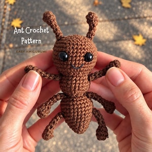 May include: A brown crocheted ant amigurumi toy with two antennae, six legs, and black plastic eyes. The text "Ant Crochet Pattern" and "EASY AMIGURUMI" is printed in white on the upper left side of the brown yarn-based insect figure.