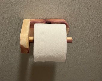 May include: A wooden toilet paper holder with a roll of white toilet paper. The holder is made of cedar wood and has a natural finish.