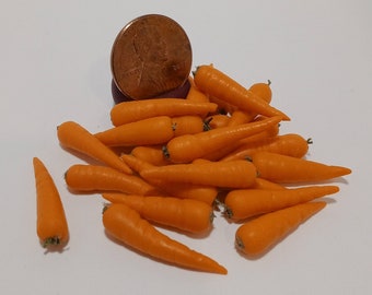 May include: A pile of miniature orange carrots with green tops. A U.S. penny is next to the carrots for scale. The carrots are on a white surface.