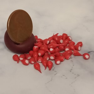 May include: A pile of red and white candy radishes, a popular edible decoration for miniature dollhouses and fairy gardens.