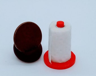 May include: A miniature white paper towel roll on a red plastic holder. A brown coin is in the background.