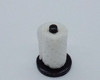 May include: A white paper towel roll on a black metal stand. The stand has a round base and a small black knob on top.