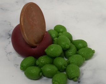 May include: A pile of small, green, round, plastic limes, with a copper penny on top of a red, round, plastic base.