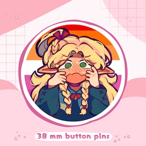 Może przedstawiać: Pin o średnicy 38 mm przedstawiający postać z kreskówki o blond włosach, zielonych oczach i różowych policzkach. Postać ma na sobie niebiesko-czarną odzież z czerwoną muszką. Pin ma na tle tęczową flagę dumy.