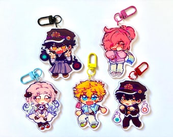 May include: Five acrylic keychains featuring stylized anime characters with vibrant colors. Each charm includes a colored plastic clasp. The designs include characters with dark uniforms, pink hair, and light hair, all rendered in a chibi art style.