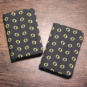 May include: Two small black notebooks with a yellow "O" pattern.