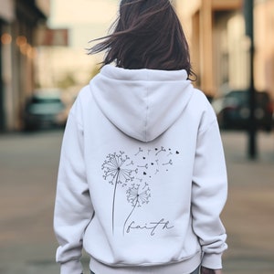 Pu&ograve; includere: Felpa bianca con un disegno di dente di leone nero e la parola "faith" stampata sul retro.