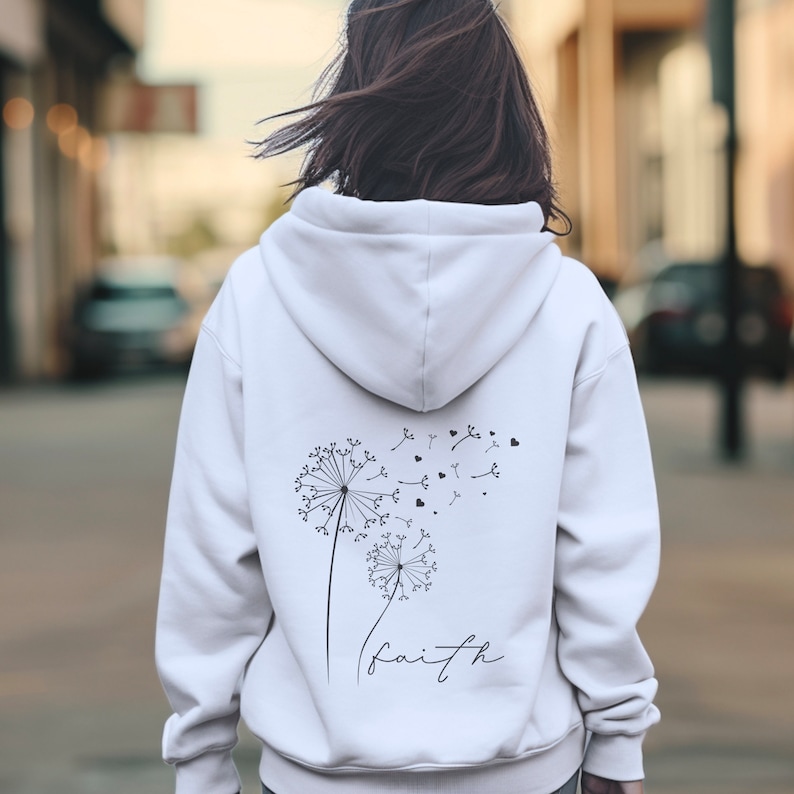 Pu&ograve; includere: Felpa bianca con un disegno di dente di leone nero e la parola "faith" stampata sul retro.