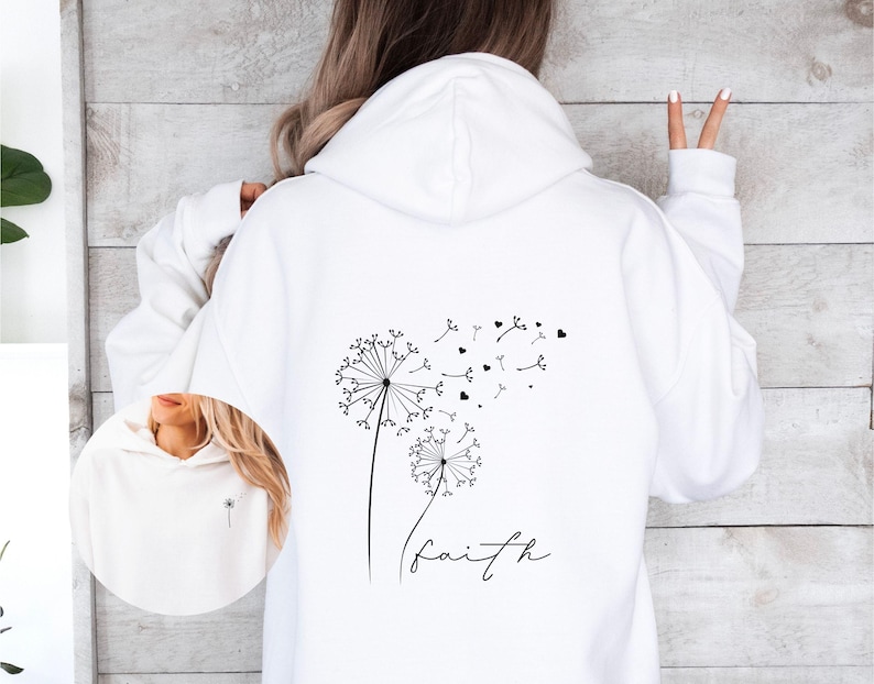 Pu&ograve; includere: Felpa bianca con un design a dente di leone nero e la parola "faith" stampata sul davanti.