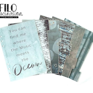 Puede incluir: Un conjunto de separadores de planificador con varios diseños y texturas. Los separadores presentan una paleta de colores azules, grises y plateados, con patrones que incluyen escamas y rayas. Un separador tiene el texto "You can find me where the Music meets the Ocean."