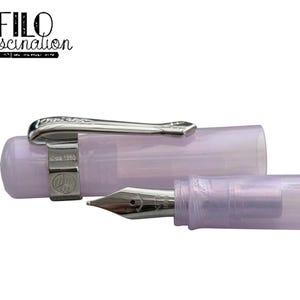 May include: A lavender-colored fountain pen with a silver clip and nib. The pen is partially disassembled, with the cap and body separated. The text "FILO fascination" is in the upper left corner.