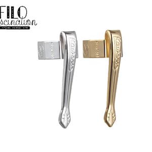 May include: Two pen clips, one silver and one gold, are displayed against a white background. The silver clip is on the left, and the gold clip is on the right. Each clip has a rectangular piece with the text "since 1883" and the brand name "Aurora" on the curved body.