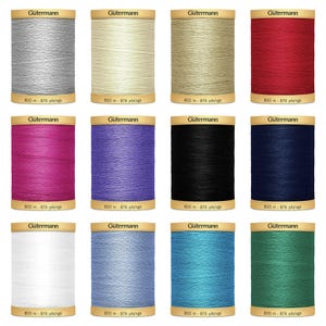 May include: Twelve spools of Gütermann thread in a variety of colours, including white, red, blue, black, pink, purple, beige, grey, light blue, turquoise, and green. Each spool is labelled with the brand name "Gütermann" and the length of the thread in metres and yards.