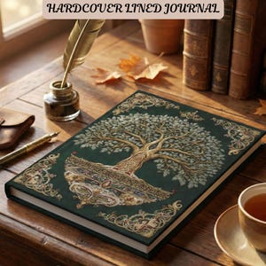 May include: A hardcover lined journal with a green cover featuring a detailed tree design in gold and white. The journal is open on a wooden table, next to a cup of tea, a pen, and an inkwell. The text "HARDCOVER LINED JOURNAL" is at the top.